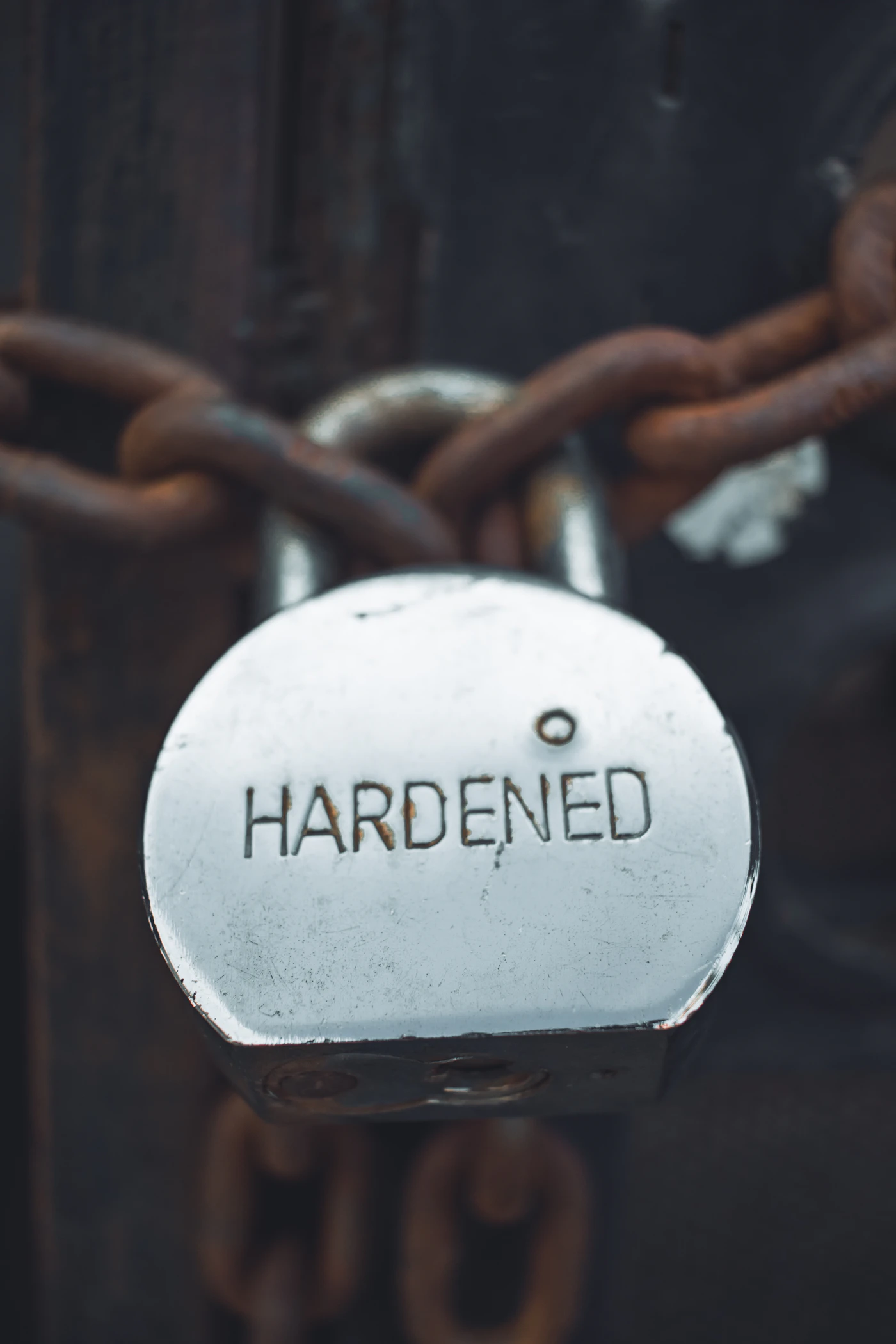 A padlock stamped HARDENED, secured shut on a metal chain