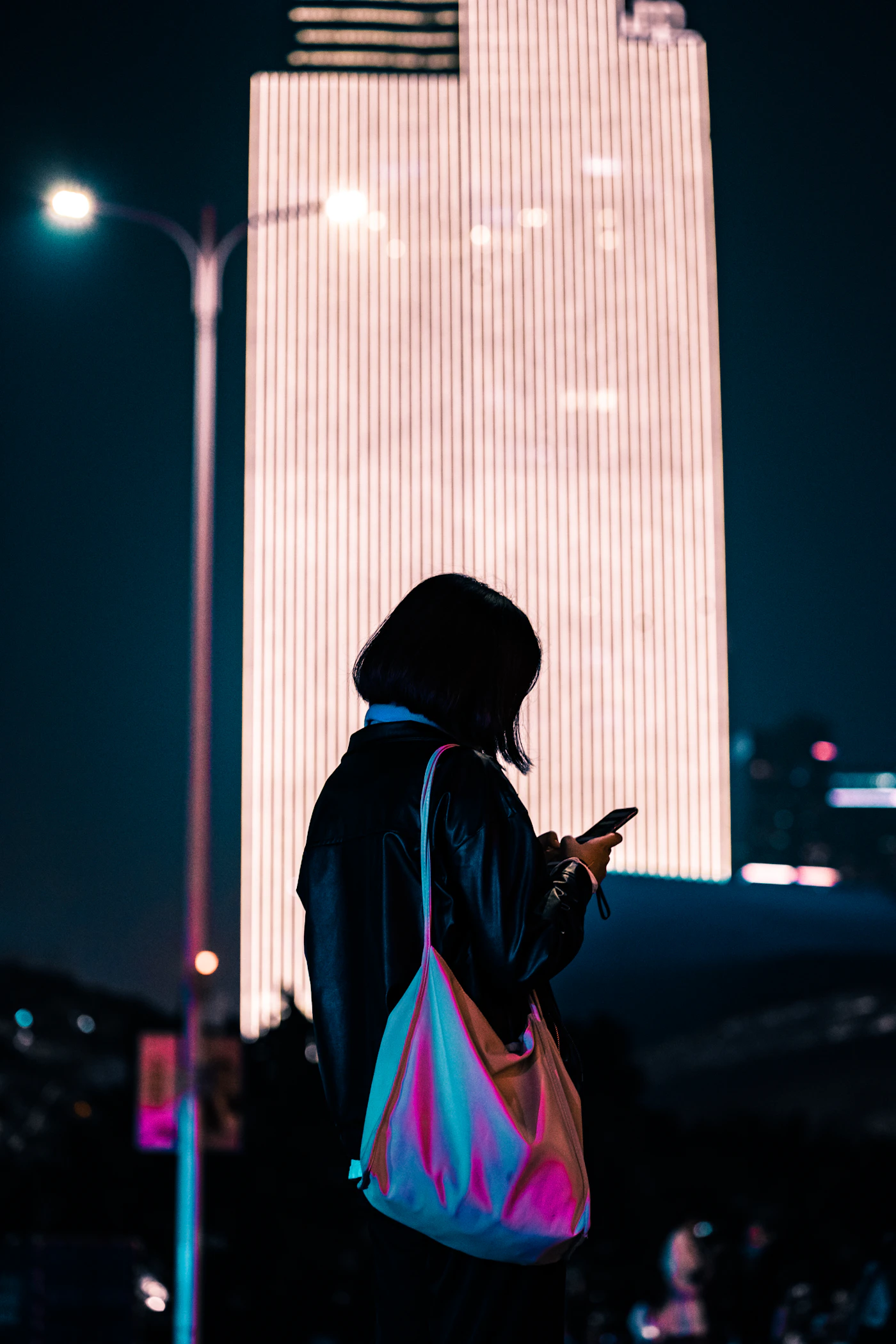 Femme qui consulte son téléphone la nuit en ville
